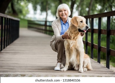 happy senior woman with golden retriever dog on wooden bridge - Powered by Shutterstock