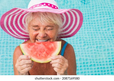 Happy senior woman having party in the swimming pool - Beautiful senior lady sunbathing and relaxing in a private pool during summertime - Powered by Shutterstock