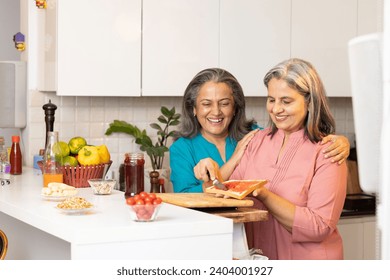 Happy senior woman and her friends making healthy fruit sandwich in the kitchen. - Powered by Shutterstock