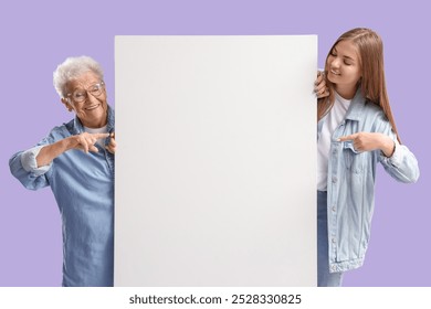 Happy senior woman and her granddaughter pointing at blank poster on purple background - Powered by Shutterstock