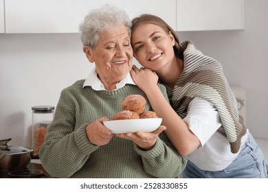 Happy senior woman and her granddaughter with plate of tasty cupcakes in kitchen at home - Powered by Shutterstock