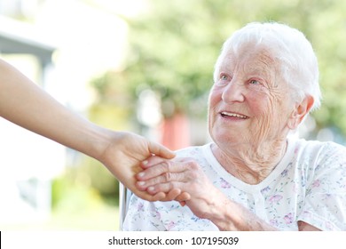 Happy Senior Woman Holding Hands With Caretaker