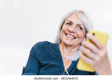 Happy Senior Woman Listening A Music Playlist On Her Mobile Phone - Elderly Grandmother Making Video Call - Focus On Lady's Smile