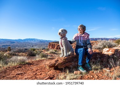 Happy Senior Woman On An Outdoor Hike With Her Dog. Enjoying Nature On A Sunny Day. Enjoying A Scenic Overlook In St. George, Utah