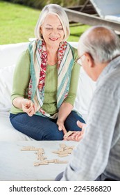 Happy Senior Woman Playing Dominoes With Man At Nursing Home Porch