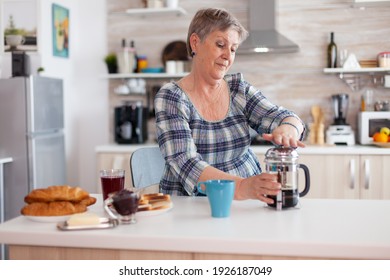 Happy senior woman pushing on french press while preparing coffee for breakfast. Elderly person in the morning enjoying fresh brown cafe espresso cup caffeine from vintage mug filter relax refreshment - Powered by Shutterstock