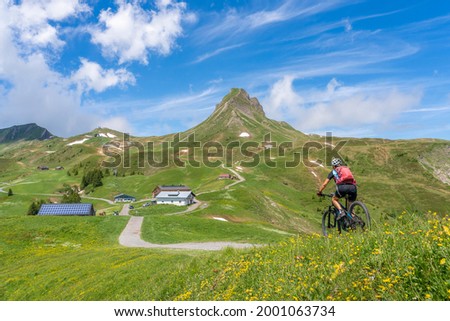 happy senior woman riding her electric mountain below Mittagsspitze summit near the  village of Damuels in the Bregenz Forest mountain of Vorarlberg, Austria
