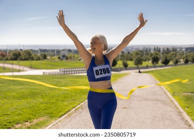 Happy senior woman running across the finish line - Mature woman running marathon race. - - Powered by Shutterstock