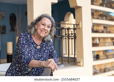 A happy senior woman smiles while posing on a balcony - Powered by Shutterstock