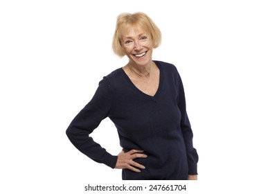 Happy senior woman standing with hand on hip against white background