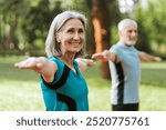 Happy senior woman stretches gracefully in a vibrant outdoor yoga class, surrounded by lush green trees and warm sunlight. Healthy lifestyle concept