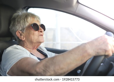 Happy senior woman in sunglasses driving automobile. - Powered by Shutterstock