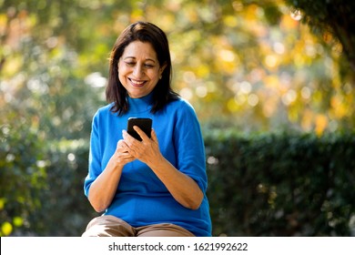 Happy senior woman text messaging using mobile phone