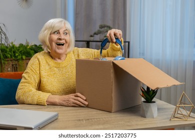 Happy senior woman unpacking delivery parcel with headphones at home. Smiling satisfied grandmother shopper, online shop customer opening cardboard box receiving purchase gift by fast postal shipping - Powered by Shutterstock