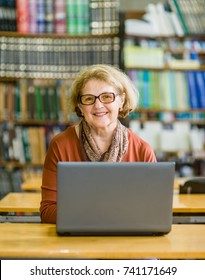 Happy Senior Woman Using Laptop In Library