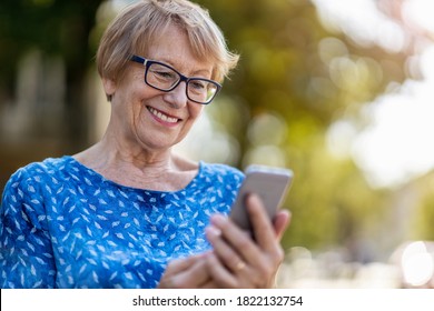 Happy Senior Woman Using Mobile Phone Outdoors
