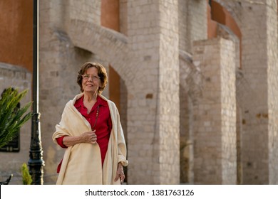 Happy Senior Woman Walking Around A Mexican Catholic Church Square. Plaza Fundadores, Durango, México.