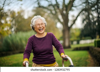Happy Senior Woman Walking With A Walking Frame.