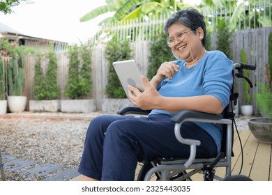 Happy senior woman in wheelchair using digital tablet at home. - Powered by Shutterstock