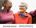 Happy senior women from different ethnicities laughing together outdoor - Multiracial mature friends having fun - Joyful elderly lifestyle - Focus on right female face