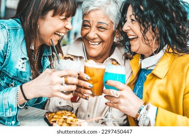 Happy senior women drinking cocktail glasses sitting at bar table - Group of best friends enjoying happy hour cheering drinks at pub restaurant - Life style concept with girls hanging out together - Powered by Shutterstock