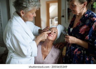 Happy Senior Women Friends In Bathrobes Applying Anti Wrinkle Patches Indoors At Home, Selfcare Concept.