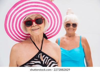 Happy senior women having party in the swimming pool - Elderly friends relaxing at a pool party - Powered by Shutterstock