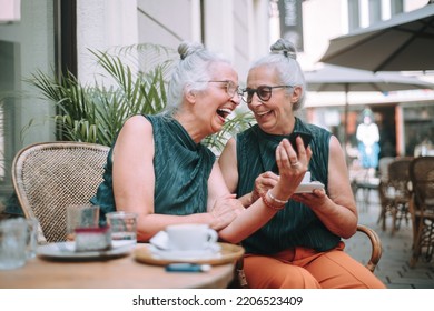 Happy senior women twins having coffee break in city, smiling and talking. - Powered by Shutterstock