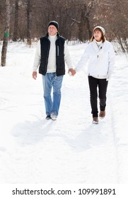 Happy Seniors Couple Walking In Winter Park. Elderly Mature People