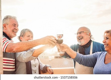Happy seniors friends drinking red wine on terrace sunset - Pensioners people having fun enjoying time together outdoor - Elderly retirement lifestyle concept