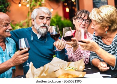 Happy Seniors Having Fun Toasting Red Wine At Dinner Garden Party - Retired Couples Drinking At Restaurant Together - Dinning Friendship Concept On Warm Vivid Filter - Focus On Bearded Hipster Man