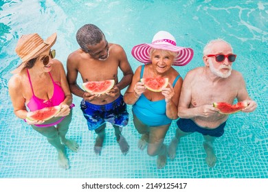 Happy seniors having party in the swimming pool - Elderly friends at a pool party during summertime - Powered by Shutterstock