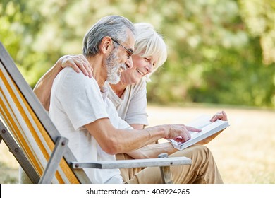 Happy seniors reading a book together in the nature in summer - Powered by Shutterstock