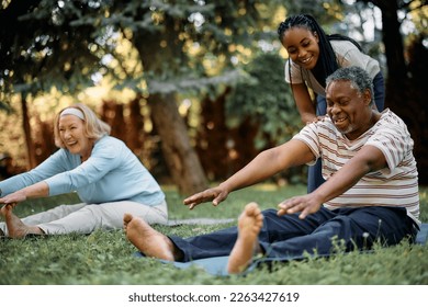 Happy seniors stretching while having exercise class with physiotherapist in backyard of residential care home. Focus is on African American man. - Powered by Shutterstock