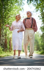 Happy Seniors Talking And Having Fun While Taking A Walk In The Park