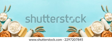 Happy Shavuot - Religious Jewish holiday concept with dairy products, cheese, traditional bread, milk bottles, wheat  on blue background, copy space, banner.