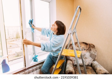 Happy Shy Cheerful Smiling Mature Woman Cleaning Window. Concept Of Household And People In Retirement. Caucasian Woman Middle Age. Active Seniors Concept. Elderly Woman Cleaning Apartment - Powered by Shutterstock