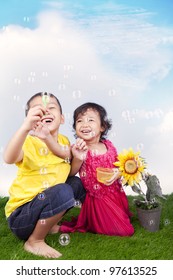 Happy sibling playing soap bubbles on the green grass