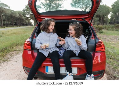 Happy Siblings Eating Food In Car Trunk