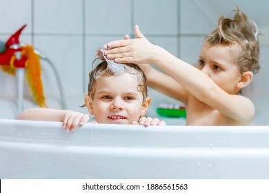 Happy siblings: Two little healthy twins children playing together with water by taking bath in bathtub at home. Kid boys having fun together. children washing heads and hairs with shampoo - Powered by Shutterstock