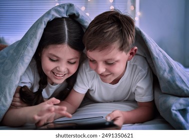 Happy siblings, watching and night with tablet on bed for watching, entertainment or online subscription at home. Children, brother and sister with smile on technology in bedroom sheets for cartoon - Powered by Shutterstock