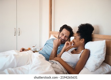 Happy, silly and goofy couple bonding in bed, sharing intimate relationship joke and moment. Young interracial husband and wife laughing, loving and enjoying lazy morning relaxing indoors together - Shutterstock ID 2194265631