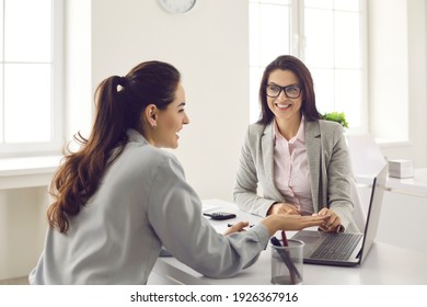 Happy single business woman meeting and consulting insurer, bank manager, financial advisor or loan broker. Smiling real estate agent or architect talking to client and showing house design on laptop