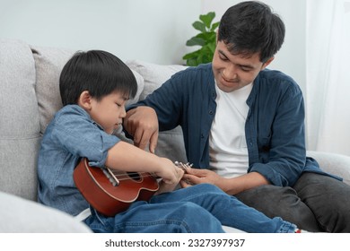 Happy single father playing learning music with the little boy. Funny family is happy and excited in the house. Father and son having fun spending time together. Vacant time, holiday