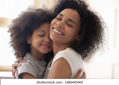 Happy single foster mother embracing cute little adopted daughter head shot close up image. Smiling loving family of two bonding, hugging, cuddling, having fun together. Positive tender family moment.