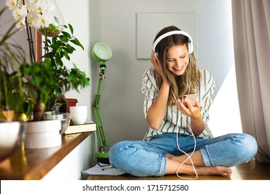 happy single woman comunicating and listening music on the desk next to the plants and bright window, work from home, stay at home.