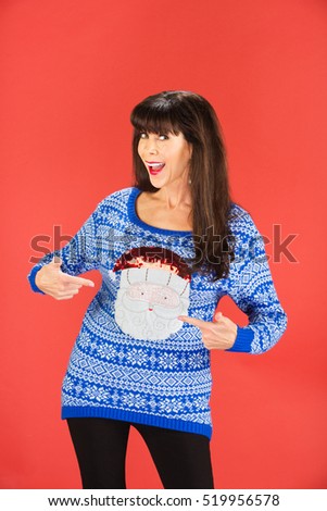 Happy single woman pointing to her ugly blue sweater with Santa Claus face on it