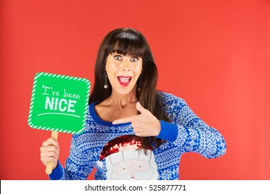 Happy Single Woman In Ugly Knitted Sweater Pointing To Nice Sign Over Red Background