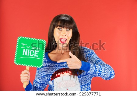 Happy single woman in ugly knitted sweater pointing to nice sign over red background