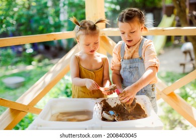 Happy Sister Kids Play With Sand And Water In Sensory Baskets On The Outdoor Sensory Table, Sensory Early Development, Montessori. Toddler And Big Sister Play With Sand, Soft Focus